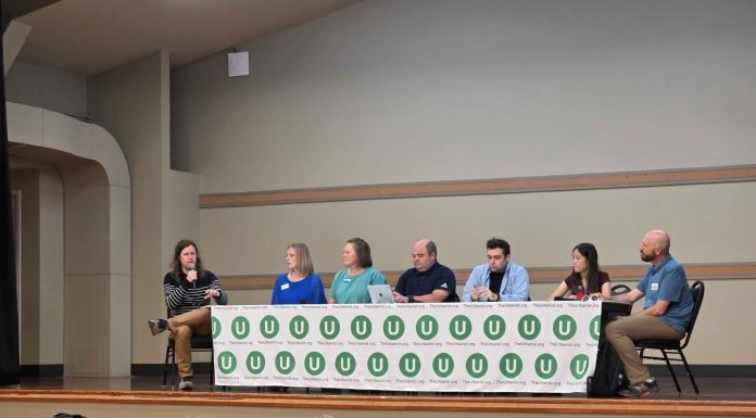 Join us for The Urbanist January Socials and North Sound Election Debrief The six panelists sit at a table with the Urbanist U logo on it and Ryna Packer is off to the side moderating.