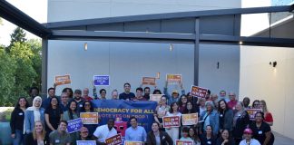 Op-Ed: Renew Democracy Vouchers, Vote Yes on Seattle Prop 1 A group shot of more than 50 campaign supporters for Yes on Prop 1 holding signs.