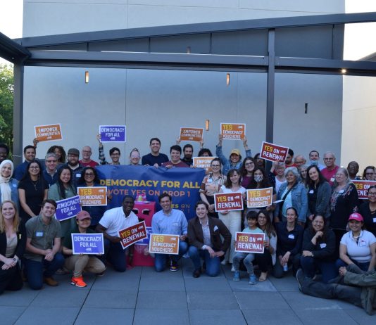 Op-Ed: Renew Democracy Vouchers, Vote Yes on Seattle Prop 1 A group shot of more than 50 campaign supporters for Yes on Prop 1 holding signs.
