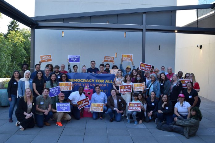 A group shot of more than 50 campaign supporters for Yes on Prop 1 holding signs.