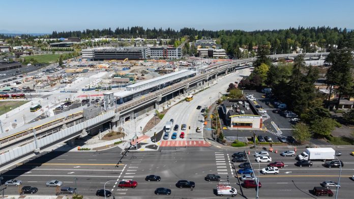 An aerial image shows an elevated light rail station next to a big staging area and a busy collector road.
