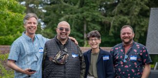 The four candidate stand in a line smiling with trees in the background.