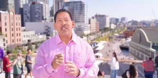 Harrell weather a pink button up shirt with pedestrians on the Overlook Walk in the background.