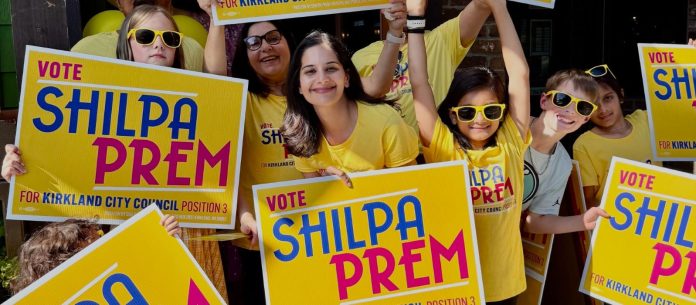 Prem and young supporters pose with yellow campaign shirts and yard signs.
