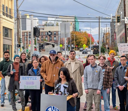 Rinck Launches ‘Better Bus Lanes’ Campaign with Transit Advocates More than two dozen advocates stand behind Rinck at the bus stop at 12th Avenue and Union Street, with Madison Street in the background.