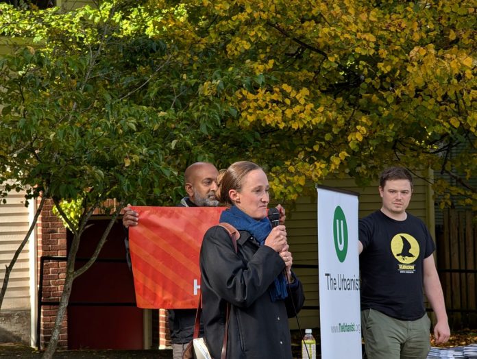 Katie Wilson at Urbanist Rally - Trumm 20251019 Wilson holds a mic and two volunteers who banners for The Urbanist and for Seattle Tech4Housing.