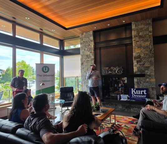 Join Us for The Urbanist Winter Holiday Party on December 9th Doug Trumm speaks in front of a group of urbanist supporters with a fireplace behind.