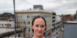 Katie Wilson Takes 91-Vote Lead in Dramatic Seattle Mayor Race Wilson stands on a rooftop in Capitol Hill wearing a Mona Lisa smile. She's a White middle-aged woman with dark hair.