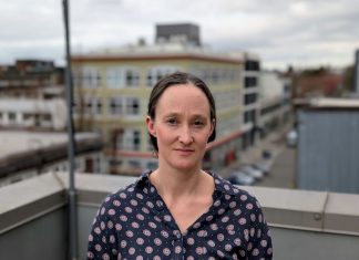 Katie Wilson Takes 91-Vote Lead in Dramatic Seattle Mayor Race Wilson stands on a rooftop in Capitol Hill wearing a Mona Lisa smile. She's a White middle-aged woman with dark hair.