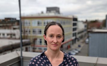 Katie Wilson Takes 91-Vote Lead in Dramatic Seattle Mayor Race Wilson stands on a rooftop in Capitol Hill wearing a Mona Lisa smile. She's a White middle-aged woman with dark hair.