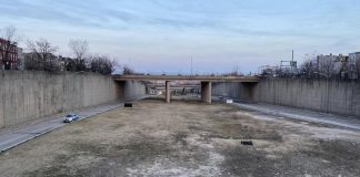 Book Review: How a Highway Map Wrecked Baltimore A barren trenched has an access road on the city but empty field down the middle with bridges spanning the trench to connect the street grid.
