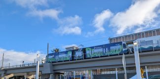 Urbanist Podcast: A Light Rail Opening and Police Accountability Door Closing A line of people approach Federal Way Downtown Station, with a train waiting at the elevated platform.