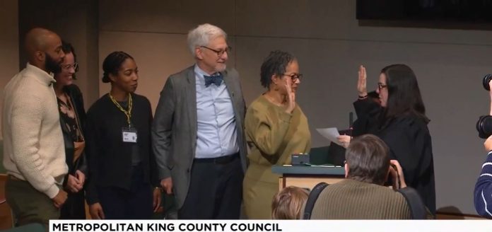 Rhonda Lewis sworn in on King County TV Lewis holds up her right hand to do the oath of office with a King County judge. Lewi's family is by her side.