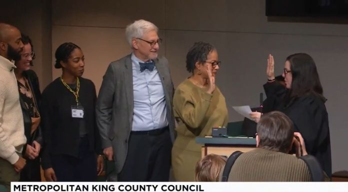 King County Council Appoints Top Zahilay Aide to Vacant Council Seat Lewis holds up her right hand to do the oath of office with a King County judge. Lewi's family is by her side.