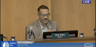 Seattle Approves Controversial Police Guild Contract, Three Councilmembers Dissent Councilmember Rob Saka sits on the council dais in a tan sportscoat.
