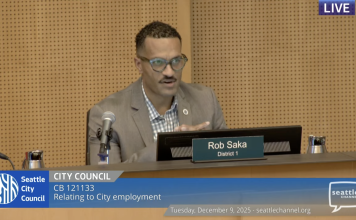 Seattle Approves Controversial Police Guild Contract, Three Councilmembers Dissent Councilmember Rob Saka sits on the council dais in a tan sportscoat.