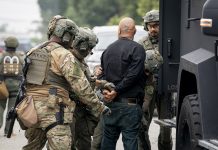 UW Report: Immigration Agents Still Accessing WA Driver Data An image of I.C.E. "enforcement and removal operation" in Los Angeles provided by the Department of Homeland Security shows three large agents in camo and battle helmets handcuffing a bald man.