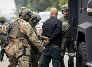 UW Report: Immigration Agents Still Accessing WA Driver Data An image of I.C.E. "enforcement and removal operation" in Los Angeles provided by the Department of Homeland Security shows three large agents in camo and battle helmets handcuffing a bald man.