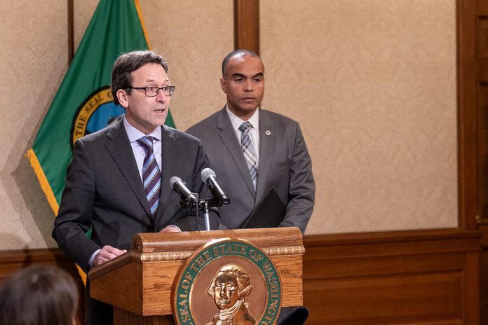 Bob Ferguson and Nick Brown Ferguson stands at the lectern with Brown over his shoulder. Both wear suits and ties.
