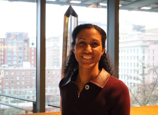 Dionne Foster Takes Office, Aiming to Tackle Housing Issues Foster smiles and stands in the atrium of Council Chambers with the south downtown skyline in the background.