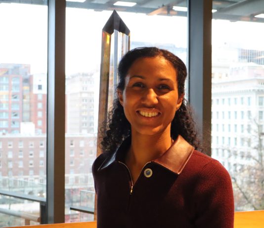 Dionne Foster Takes Office, Aiming to Tackle Housing Issues Foster smiles and stands in the atrium of Council Chambers with the south downtown skyline in the background.