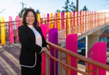 Educator Julie Kang Enters Fray in D5 Seattle Council Race Kang stands by a colorful pedestrian bridge over Aurora Avenue.