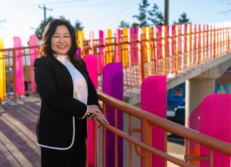 Educator Julie Kang Enters Fray in D5 Seattle Council Race Kang stands by a colorful pedestrian bridge over Aurora Avenue.