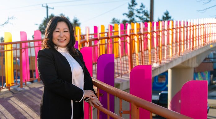 Educator Julie Kang Enters Fray in D5 Seattle Council Race Kang stands by a colorful pedestrian bridge over Aurora Avenue.