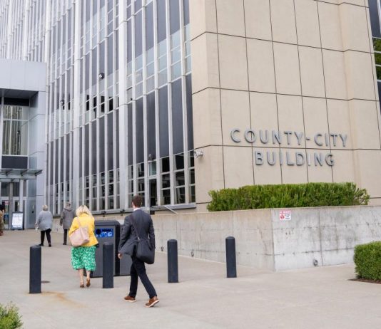 ICE’s Tacoma Detention Center Targeted in New Lawsuit Alleging Abuses A stream of people in formal clothes walk into a modern concrete and plate class courthouse building