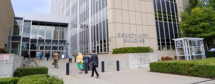 Pierce County Superior Court and Municipal-Court- via Tacoma A stream of people in formal clothes walk into a modern concrete and plate class courthouse building