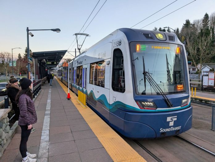 Riders wait as a train pulls into Columbia Station Station, which in the median of a four-lane road.